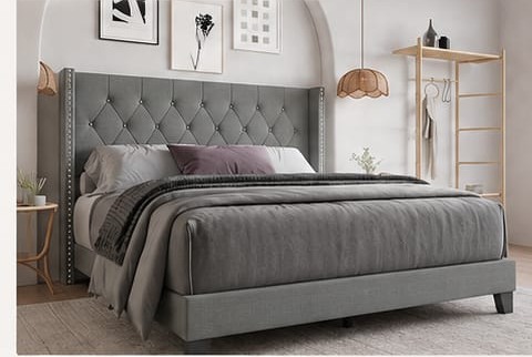 A grey tufted wingback upholstered bed made up in a bedroom